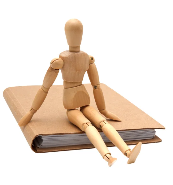 Wooden man sitting on brown notebook Stock Photo