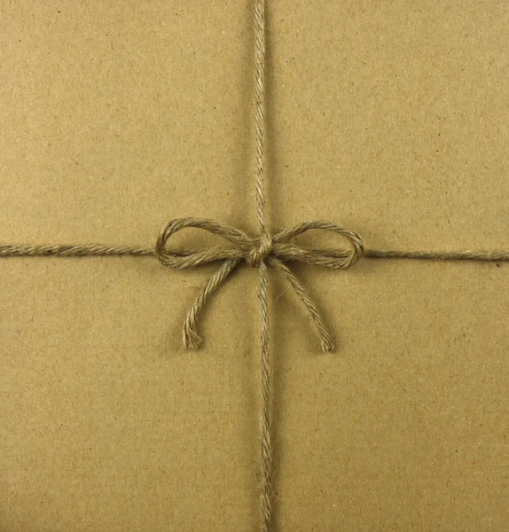 Cuerda atada en un lazo, sobre papel reciclado marrón — Foto de Stock