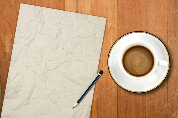 Papier und eine weiße Kaffeetasse auf einem Holztisch — Stockfoto