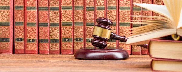 Law concept - Open law book with a wooden judges gavel on table in a courtroom or law enforcement office isolated on white background. Copy space for text