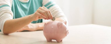 Kadın, para biriktirmek ve finansal konsept için domuzcuğa para yatırıyor.