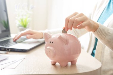 Kadın, para biriktirmek ve finansal konsept için domuzcuğa para yatırıyor.