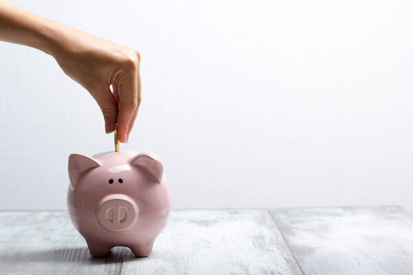 woman hand putting money coin into piggy for saving money wealth and financial concept