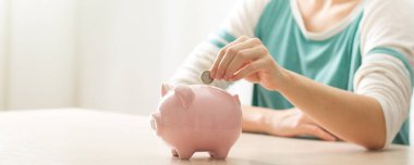 Kadın, para biriktirmek ve finansal konsept için domuzcuğa para yatırıyor..