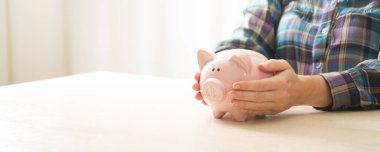 Kadın, para biriktirmek ve finansal konsept için domuzcuğa para yatırıyor..