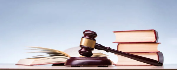 Law concept - Open law book with a wooden judges gavel on table in a courtroom or law enforcement office isolated on white background. Copy space for text