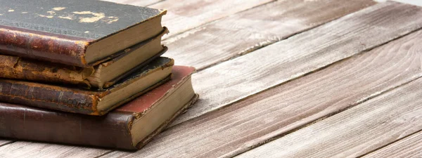 Vintage leather books stack on old rustic wooden surface — Stock Photo, Image