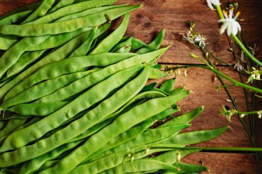 Taze taze taze taze fasulyelerin kırsal ve doğal görüntüsü. Sağlıklı yiyecekler ve yemek pişirme uzmanları. Ahşap arka planda bir grup yeşil fasulye..