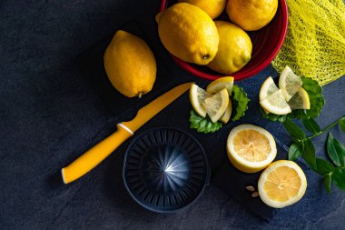 Limon ve limon dilimlerinin koyu veya siyah çimento ya da taş yüzeyde bıçak ve sıkacağı zarif bir arka plan tasarımı. Taze ve olgun limonlar için fotokopi alanı olan üst manzara. Sağlıklı gıda arka planı.