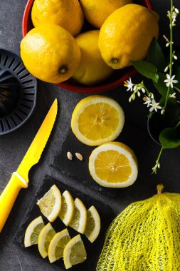 Limon ve limon dilimlerinin koyu veya siyah çimento ya da taş yüzeyde bıçak ve sıkacağı zarif bir arka plan tasarımı. Taze ve olgun limonlar için fotokopi alanı olan üst manzara. Sağlıklı gıda arka planı.