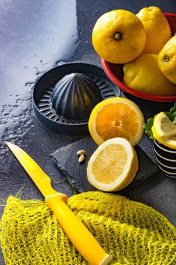 Limon ve limon dilimlerinin koyu veya siyah çimento ya da taş yüzeyde bıçak ve sıkacağı zarif bir arka plan tasarımı. Taze ve olgun limonlar için fotokopi alanı olan üst manzara. Sağlıklı gıda arka planı.
