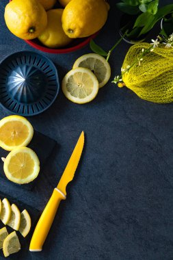 Limon ve limon dilimlerinin koyu veya siyah çimento ya da taş yüzeyde bıçak ve sıkacağı zarif bir arka plan tasarımı. Taze ve olgun limonlar için fotokopi alanı olan üst manzara. Sağlıklı gıda arka planı.