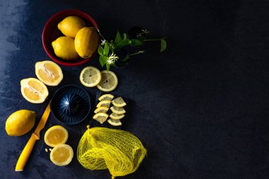Limon ve limon dilimlerinin koyu veya siyah çimento ya da taş yüzeyde bıçak ve sıkacağı zarif bir arka plan tasarımı. Taze ve olgun limonlar için fotokopi alanı olan üst manzara. Sağlıklı gıda arka planı.