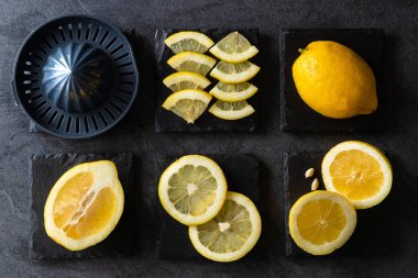 Limon ve limon dilimlerinin koyu veya siyah çimento ya da taş yüzeyde bıçak ve sıkacağı zarif bir arka plan tasarımı. Taze ve olgun limonlar için fotokopi alanı olan üst manzara. Sağlıklı gıda arka planı.