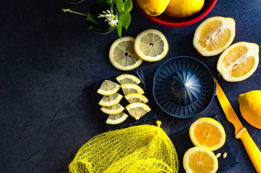 Taze ve olgun limonlar için fotokopi alanı olan en iyi manzara. Sağlıklı gıda arka planı. Limon ve limon dilimlerinin koyu ya da siyah çimento ya da taş yüzeyinde sıkma ve bıçak ile zarif bir arka plan tasarımı..