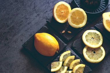 Taze ve olgun limonlar için fotokopi alanı olan en iyi manzara. Sağlıklı gıda arka planı. Limon ve limon dilimlerinin koyu ya da siyah çimento ya da taş yüzeyinde sıkma ve bıçak ile zarif bir arka plan tasarımı..