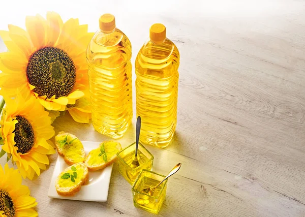 Composition with sunflower oil on white wooden table on white background. Plastic bottles with sunflower oil, fresh yellow sunflowers.Flat top view copy space.