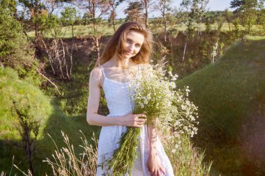 Beyaz elbiseli kız tarlada yürüyor.