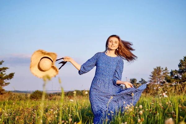 Mavi elbiseli kız tarlada yürüyor.