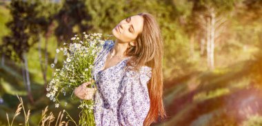 Doğada bir buket çiçekle güzel bir kız.