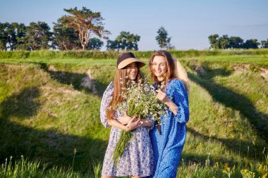 two young beautiful girls with a bouquet of flowers in nature