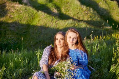 two young beautiful girls with a bouquet of flowers in nature