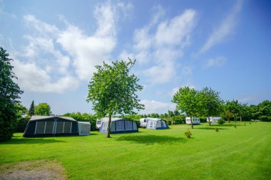 Yazın büyük yeşil bir çimenlikte çadır kampı olan bir kamp alanı.