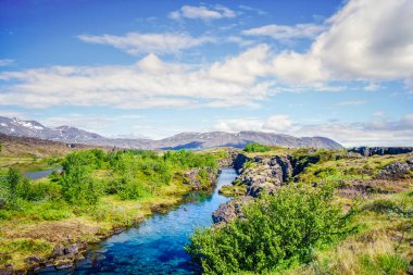 Turkuaz nehir akıntısı arka planda dağlarla birlikte vahşi İzlanda doğasında
