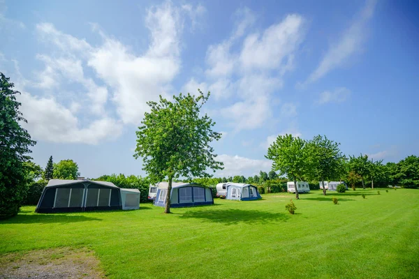 Camping site with a tent camp on a large green lawn in the summer