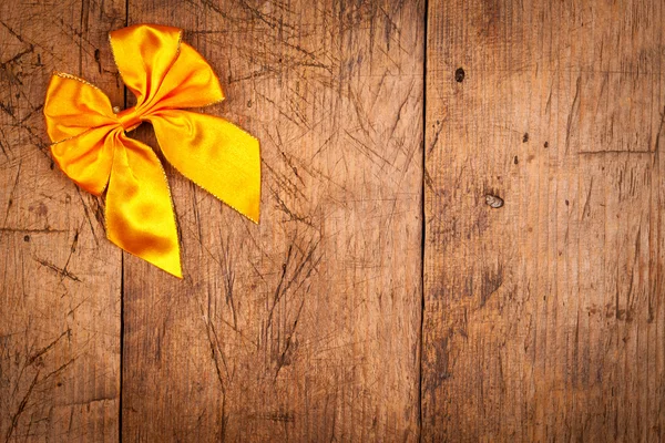 Yellow ribbon on rustic wooden background — Stock Photo, Image