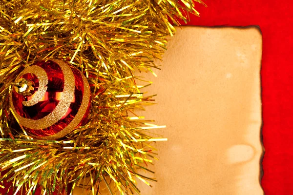 Christmas globe with golden tinsel on old paper — Stock Photo, Image