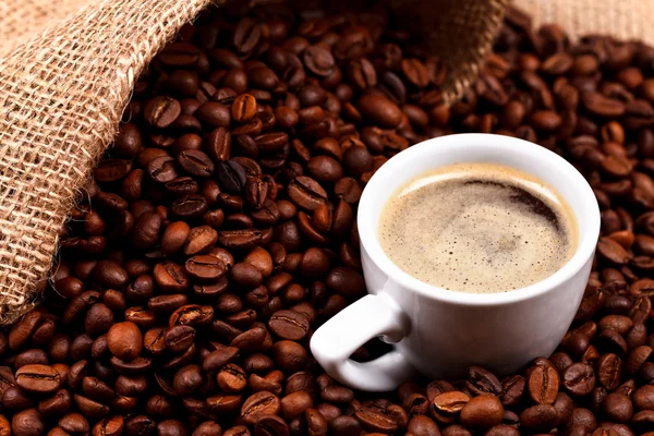 Çuvala ve bir fincan kahve kahve çekirdekleri — Stok fotoğraf