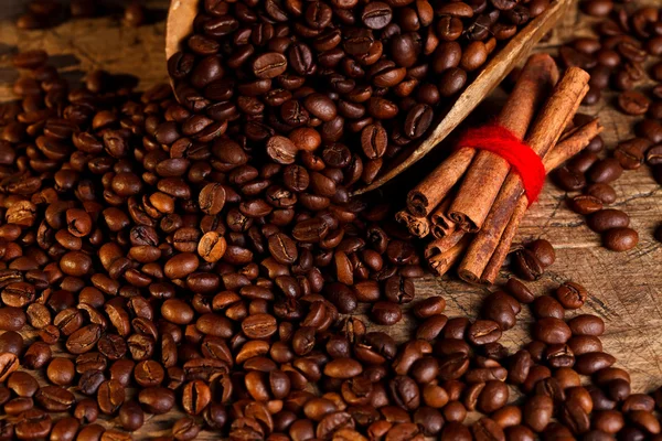 Grãos de café com canela e concha de madeira — Fotografia de Stock