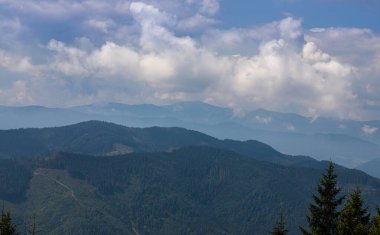 Ukrayna Karpatları 'nın dağ yamaçlarında. Dağın tepeleri ve ormanlar mavi gökyüzünün arka planında.