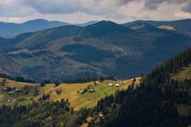 Ukrayna Karpatları 'nın dağ yamaçlarında. Dağın tepeleri ve ormanlar mavi gökyüzünün arka planında.