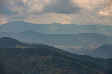 Ukrayna Karpatları 'nın dağ yamaçlarında. Dağın tepeleri ve ormanlar mavi gökyüzünün arka planında.