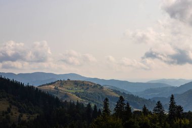Ukrayna Karpatları 'nın dağ yamaçlarında. Dağın tepeleri ve ormanlar mavi gökyüzünün arka planında.