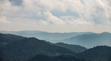 Ukrayna Karpatları 'nın dağ yamaçlarında. Dağın tepeleri ve ormanlar mavi gökyüzünün arka planında.