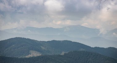 Ukrayna Karpatları 'nın dağ yamaçlarında. Dağın tepeleri ve ormanlar mavi gökyüzünün arka planında.