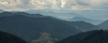 Ukrayna Karpatları 'nın dağ yamaçlarında. Dağın tepeleri ve ormanlar mavi gökyüzünün arka planında.