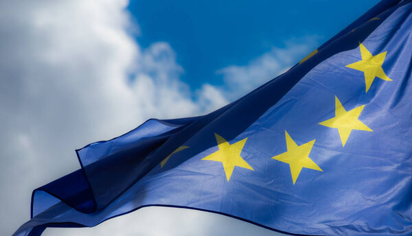 Official flag of the European Union in front of a blue sky.