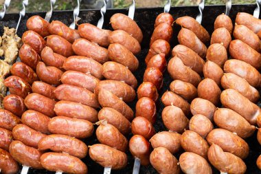 Sosisler açık havada ızgarada kızartılıyor. Sosisler geleneksel olarak gastronomik festivallerde hazırlanır. Çok doyurucu ve lezzetli bir yemek. Sokak fotoğrafı..
