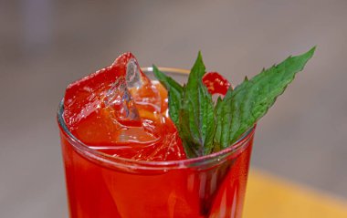 Buz küpleri ve yeşil yapraklı kırmızı içecek. .