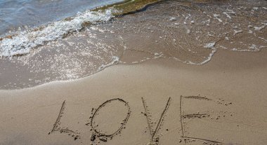 Kuma çizilmiş aşk yazısı. Gerçek ve dürüst romantik duygular kavramı. Denizde kaplıca romanı.