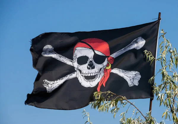 A skull and cross bones pirate flag waving in the wind.