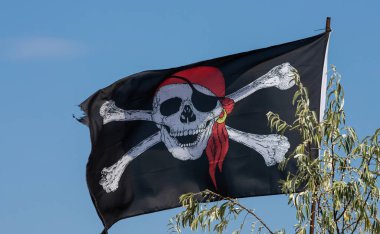 Bir kafatası ve çapraz kemikler bayrak rüzgarda sallayarak korsan.