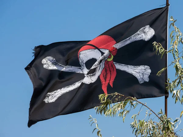 A skull and cross bones pirate flag waving in the wind.