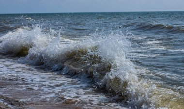 Deniz dalgaları kıyıdaki büyük kayalara çarpar ve büyük sıçramalar yaratır...