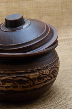 Turuncu-kahverengi renkli seramik sofra takımı. Kumaşın arka planında doğal renklerle beyaz desenli..