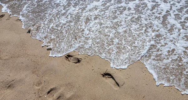 一个人在黄色沙滩上的脚印 因为他赤脚走在海边 海水冲走了他的脚印 生命的终结 — 图库照片